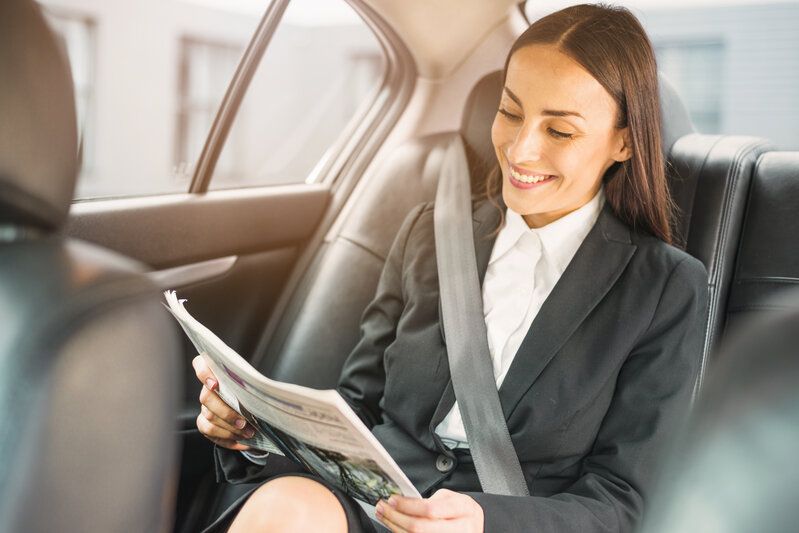 Femme d’affaires lisant le journal à l’arrière d’un taxi