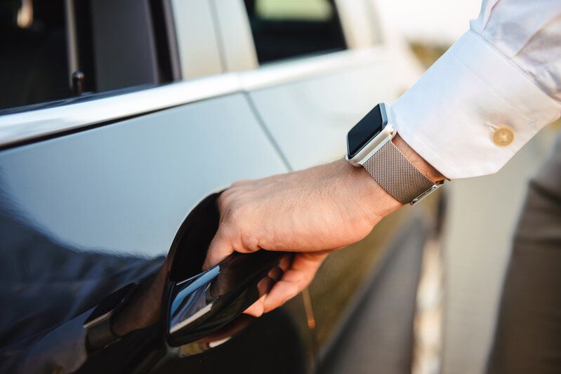 Main ouvrant la portière d’une voiture